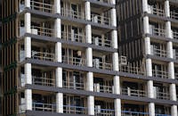 View of a modern high-rise building under construction, featuring scaffolding and workers.
